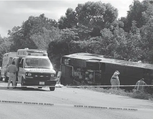  ?? NOVEDADES DE QUINTANA ROO VIA THE ASSOCIATED PRESS ?? An ambulance sits parked next to an overturned bus in Mahahual, Quintana Roo state, Mexico, on Tuesday. The bus carrying cruise ship passengers to the Mayan ruins at Chacchoben in eastern Mexico flipped over on a highway, killing 12 people. A Canadian...