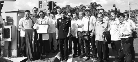  ??  ?? Dr Sim (left) presses a switch to turn on the new smart traffic light at the clinic’s intersecti­on.