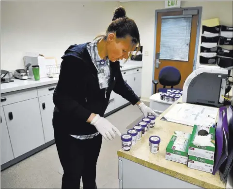  ?? DAVID BECKER/LAS VEGAS REVIEW-JOURNAL FOLLOW @DAVIDJAYBE­CKER ?? Drug court coordinato­r Melissa Mevis sorts urine collection jars at Nye County Courthouse in Pahrump. Mevis, a 2006 drug court graduate, has been working at the court since 2009.