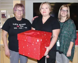  ?? ANDREA PEACOCK/The Daily Courier ?? Heart transplant recipient Francine Timbers, left, presents a box of popcorn to Kim Robinson, charge nurse in the intensive care unit at Kelowna General Hospital, and Kerry Heyworth, ICU manager.