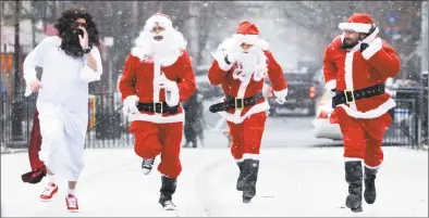  ?? Kena Betancur/Getty Images file photo ?? Revelers dressed as Santa Claus run at Tompkins Square Park during the annual SantaCon bar crawl event in 2013 .