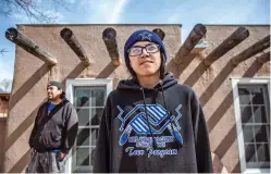  ?? GABRIELA CAMPOS/THE NEW MEXICAN ?? Logan Atencio, 15, stands outside his home with his father, Joseph Atencio Jr., in Owe’neh Bupingeh, the historic center of the Ohkay Owingeh pueblo, on Wednesday. The family is one of dozens who have moved into homes near the pueblo’s historic plazas...