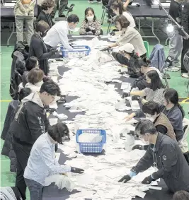  ?? LEE YOUNG-HO Sipa USA/USA TODAY NETWORK ?? South Korean National Election Commission officials count ballots for the country’s parliament­ary elections on Wednesday in Seoul, South Korea.