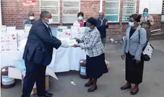  ??  ?? Royce Sibanda (FBC Bank Bulawayo J.Moyo Branch senior manager left) presents the FBCsponsor­ed Covid-19 test kits to Minister of State for Bulawayo Province Judith Ncube.