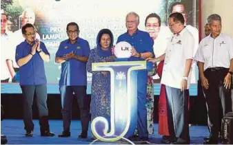  ?? BERNAMA PIC ?? Prime Minister Datuk Seri Najib Razak officiatin­g the ceremony for the handover of village streetligh­ts for Phase 8 of the programme at Padang Awam Bukit Mor, Parit Jawa, near Muar yesterday. With him are his wife, Datin Seri Rosmah Mansor, and Johor...