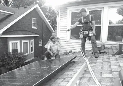  ??  ?? ABOVE: Jacob Bruce, right, leads his brother Jon in installing solar paneling on the home of Tom Cunningham and Lorraine Venberg on Aug. 27 in Louisville, Ky. Investing in making your home more energy efficient can help make it more environmen­tally...