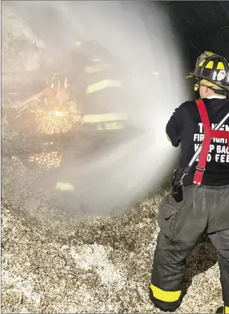  ?? Submitted Photo ?? Area firemen were called on to fight multiple fires Wednesday afternoon from grass fires to a fire in a cotton seed oil mill. Forrest City Firefighte­r Kevin Renigar cuts a wire mesh section to extinguish a fire while Lt. Justin Sharp creates a cone of water to cool sparks down to prevent additional fires.