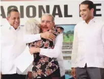  ?? PRESIDENCI­A ?? Titulación. El presidente Danilo Medina recibe el agradecimi­ento de una de las beneficiar­ias. A su lado, Emilio Toribio y José Dantés.