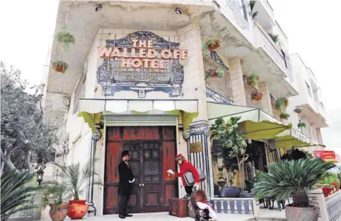  ??  ?? A bellboy stands outside street artist Banksy's newly opened Walled Off hotel in the Israeli occupied West Bank town of Bethlehem. — AFP photos