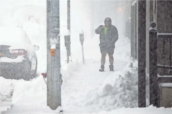  ?? JOSHUA BESSEX/AP ?? A pedestrian braves the elements Friday morning in Buffalo, N.Y.