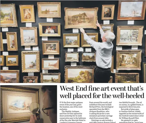  ??  ?? Ron Hodgson, top, hangs paintings on the opening day at the Mayfair Antiques and Fine Art Fair. Above, exhibitor Simon Shore studies a painting of the Battle of Waterloo by JMW Turner.