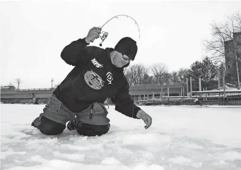  ?? PAUL A. SMITH / MILWAUKEE JOURNAL SENTINEL ?? Tim Hyvonen of Oak Creek prepares to land a steelhead while ice fishing on the Root River in Racine on Wednesday.