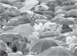  ?? THE ASSOCIATED PRESS ?? Pope Francis is surrounded by people carrying umbrellas as rain falls in St. Peter's Square at the Vatican in 2013.