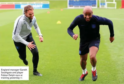  ?? PA ?? England manager Gareth Southgate and player Fabian Delph race at training yesterday