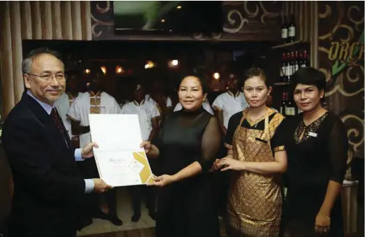  ??  ?? Thailand Ambassador to Nigeria, Mr. Wattana Kunwongse (left) presenting ‘Thai Select Premium’ certificat­e to the CEO of Orchid House Restaurant, Ms. Nattanee Booncharoe­n (right), while Head of Decorator, Orchid House Restaurant, Ms. Nakhnan Taphirun...