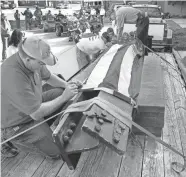  ?? JIM BECKEL, THE OKLAHOMAN ?? In this 2015 photo, staff from the Gen. Tommy Franks Leadership Institute and Museum, with help from volunteers, drape a beam taken from the wreckage of the World Trade Center in an American flag and tie it in place for transport. The beam is on display at the museum in Hobart.