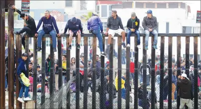  ?? AP PHOTO ?? Central American migrants sit on top of the border wall on the beach during a gathering of migrants living on both sides of the border, Sunday.