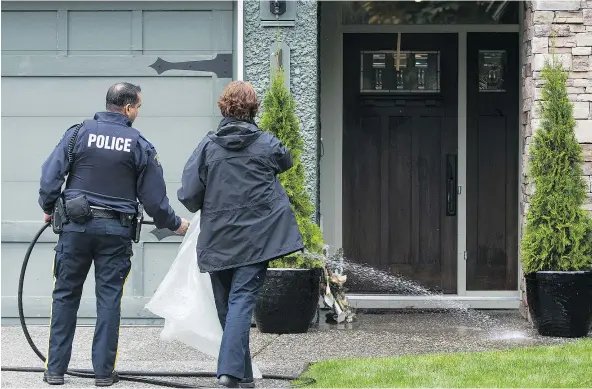  ?? RICHARD LAM/PNG ?? RCMP officers clean blood from the front entry of a house on the 14300-block of Crescent Road in Surrey following an early morning shooting that left one man dead and a woman in serious condition.