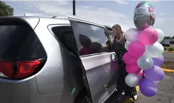  ?? AP ?? TRIED AND TRUE TRANSPORAT­ION: Melanie Matcheson loads balloons into her Chrysler Pacifica in Southingto­n, Conn.
