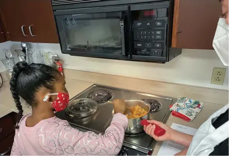  ?? (Special to The Commercial/Arts & Science Center for Southeast Arkansas) ?? A student (left) cooks apples with help from assistant instructor Eleanor Miller with the cooking school Kids Cook! during the fall 2021 series of CrEATe Lab. The program returns to the center on Jan. 22.