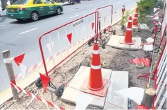  ?? ?? DANGER ZONE: Manholes on a road divider near Lat Phrao Soi 49 are covered with concrete plates and fenced off to warn pedestrian­s not to enter the area.