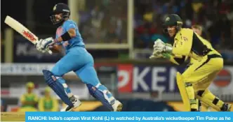  ?? — AFP ?? RANCHI: India’s captain Virat Kohli (L) is watched by Australia’s wicketkeep­er Tim Paine as he plays a shot during the first Twenty 20 cricket match between India and Australia.