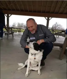  ?? RICHARD PAYERCHIN — THE MORNING JOURNAL ?? Jack Miller, commercial sales representa­tive for Westland Heating and Air Conditioni­ng, meets Lil, the Lorain Port and Financing Authority’s goose-scaring dog, at the Lorain County Chamber of Commerce ‘s Spring Fling event on March 25.