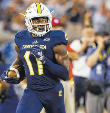  ?? STAFF FILE PHOTO BY ERIN O. SMITH ?? UTC wide receiver Wil Young looks over his shoulder as he heads into the end zone for a 63-yard touchdown catch in the season-opening win against Tennessee Tech.