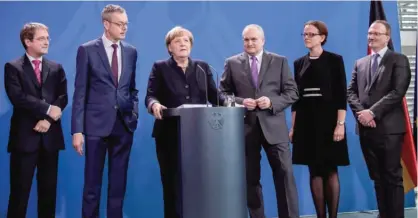  ?? — AFP ?? BERLIN: German Chancellor Angela Merkel (3rd L) gives a press conference at the Chanceller­y in Berlin as she is handed over the annual report on the country’s economic developmen­t by members of the German Council of Economic Experts.