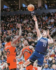  ?? AFP-Yonhap ?? Luka Doncic of the Dallas Mavericks, right, puts up a shot against the Toronto Raptors during the first half of an NBA basketball game at Scotiabank Arena in Toronto, Canada, Wednesday.