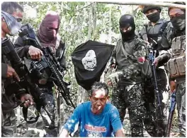  ??  ?? Closely watched: Abu Sayyaf gunmen holding hostages including Mohd Ridzuan (second from right) and (inset) another Malaysian sailor Abdul Rahim Summas at two undisclose­d locations on Jolo island.