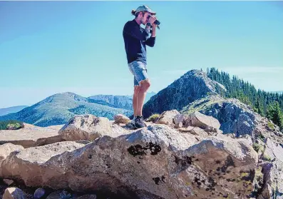  ?? EDDIE MOORE/JOURNAL ?? ABOVE: Ethan Linck, a postdoctor­al fellow in biology at UNM, looks for birds from Deception Peak in the Sangre de Cristo Mountains earlier this month.