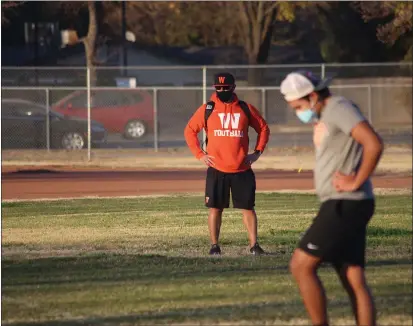  ?? PHOTOS BY CARLOS GUERRERO — DAILY DEMOCRAT ?? Woodland head varsity football coach Javier Marin looks on as his team conditions.