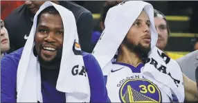  ?? BEN MARGOT / ASSOCIATED PRESS ?? Golden State Warriors' Kevin Durant smiles on the bench beside Stephen Curry during the first half of Saturday’s 108-102 preseason loss to the Denver Nuggets in Oakland, California.