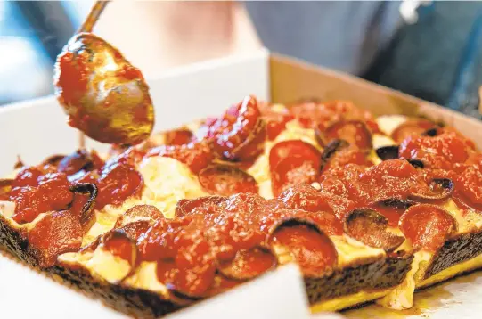  ?? PHOTOS COURTESY OF PAUL CRISP OF DISTORTED IMAGE VA ?? Glenn Allen slathers seasoned marinara atop his red-top Detroit-style pepperoni pie at Hampton-based food truck Flame and Pie.