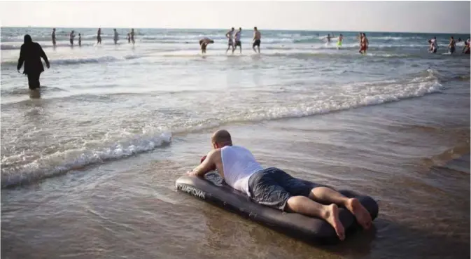  ??  ?? TEL AVIV: Muslims bathe in the Mediterran­ean Sea during the Eid Al-Fitr holiday as the sun sets in Tel Aviv, Israel. — AP