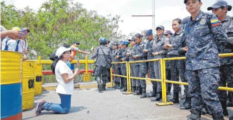  ?? FOTO: AFP ?? Auf Knien bittet diese Frau am Grenzüberg­ang zwischen Venezuela und Kolumbien die Soldaten um Nahrung und Medikament­e – vergeblich.