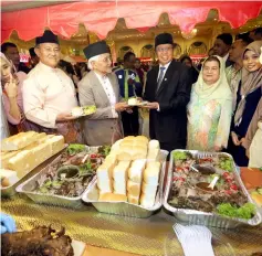  ??  ?? Abang Johari and Taib, flanked by Juma’ani (second right) and Morshidi (fith right), show the delicacies served at the Gawai Raya gathering at the old DUN Complex.