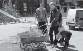  ?? AP ?? Local residents fill bottles with drinking water in Mariupol, in territory under the government of the Donetsk People’s Republic, in eastern Ukraine, on Thursday.