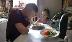  ?? — AFP ?? Valeriya, 6, the eldest daughter of Valery Kucherenko, helps her father eat lunch at their home in the town of Bila Tserkva, on April 4, 2024.