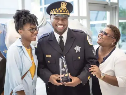  ?? RICH HEIN/SUN-TIMES ?? Chicago Police Sgt. Jermaine Harris (with sister Jaleesa, left, and mother, Diane) was honored Wednesday by the Chicago Police Memorial Foundation for his help in saving a Little League program in the Austin neighborho­od.