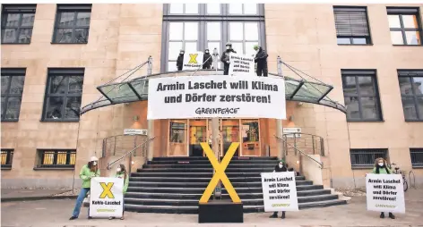  ?? FOTO: HENNING KAISER/DPA ?? Aktivisten von Greenpeace stehen am Dienstag auf dem Vordach der Staatskanz­lei in Düsseldorf. Ihnen geht der Kohleausst­ieg zu langsam.