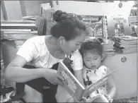  ?? GUO JUNFENG / FOR CHINA DAILY ?? A mother reads a book for her daughter at the third China Children’s Book Expo on July 10.