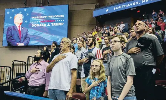  ?? EVAN VUCCI / AP ?? Seguidores de Trump se ponen en pie para el himno nacional antes del comienzo de su mitin en Southaven, en el estado sureño de Misisipi