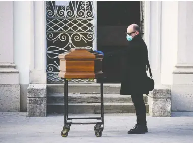  ?? PIERO CRUCIATTI/AFP VIA GETTY IMAGES ?? A man touches the coffin of his mother during a funeral service in the closed cemetery of Seriate, near Bergamo, Lombardy, Italy, on Friday during the country’s lockdown aimed at stopping the spread of the novel coronaviru­s.