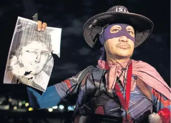  ?? AFP ?? MARKED WOMAN: A man wearing a Zorro costume holds a photo of former Philippine­s first lady Imelda Marcos during a protest at the University of Philippine­s in Manila yesterday, after Marcos, a member of the nation’s Congress, was found guilty of corruption.