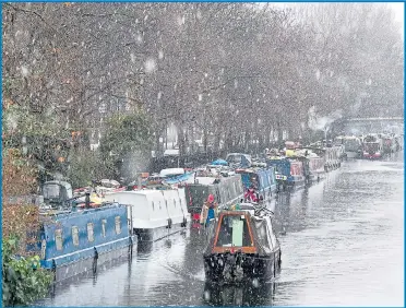  ??  ?? A boat makes its way through the snow at Little Venice on the Grand Union Canal in Westminste­r
