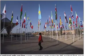  ?? (AP/Mosa’ ab Elshamy) ?? A participan­t walks past flags outside a convention center hosting the IMF and World Bank annual meetings, in Marrakesh, Morocco, on Sunday.