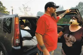  ??  ?? Walter Batt (left) and Jessica Banda load their car to evacuate their home near Red Winery and Pine Flat roads as they flee the Kincade Fire racing through the Geyservill­e area.