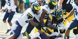  ?? CHARLIE NEIBERGALL/AP ?? Iowa RB Kaleb Johnson, center, is tackled by Michigan LBs Junior Colson, left, Kalel Mullings and DB Will Johnson, right, Saturday in Iowa City, Iowa.